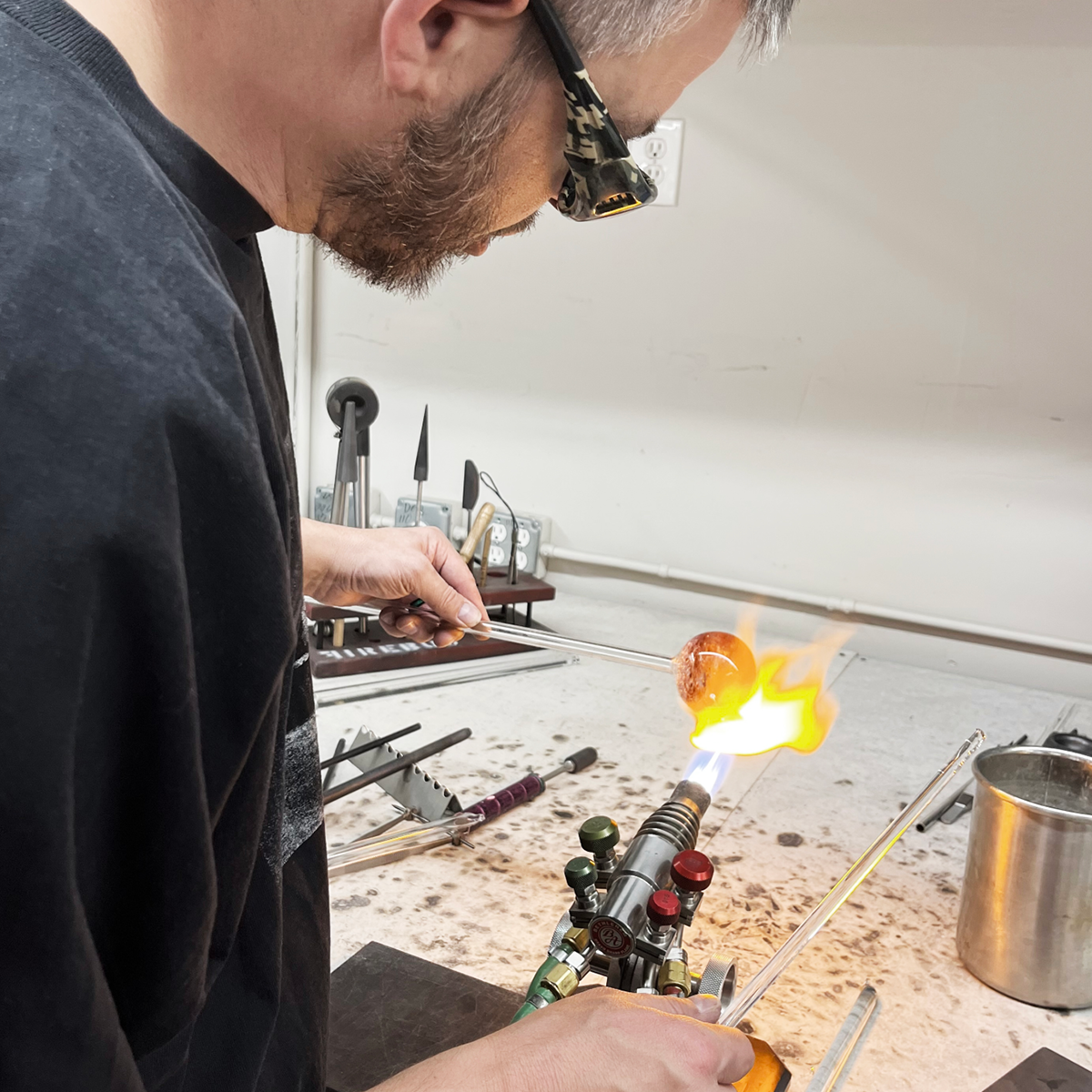 man using a torch to shape glass
