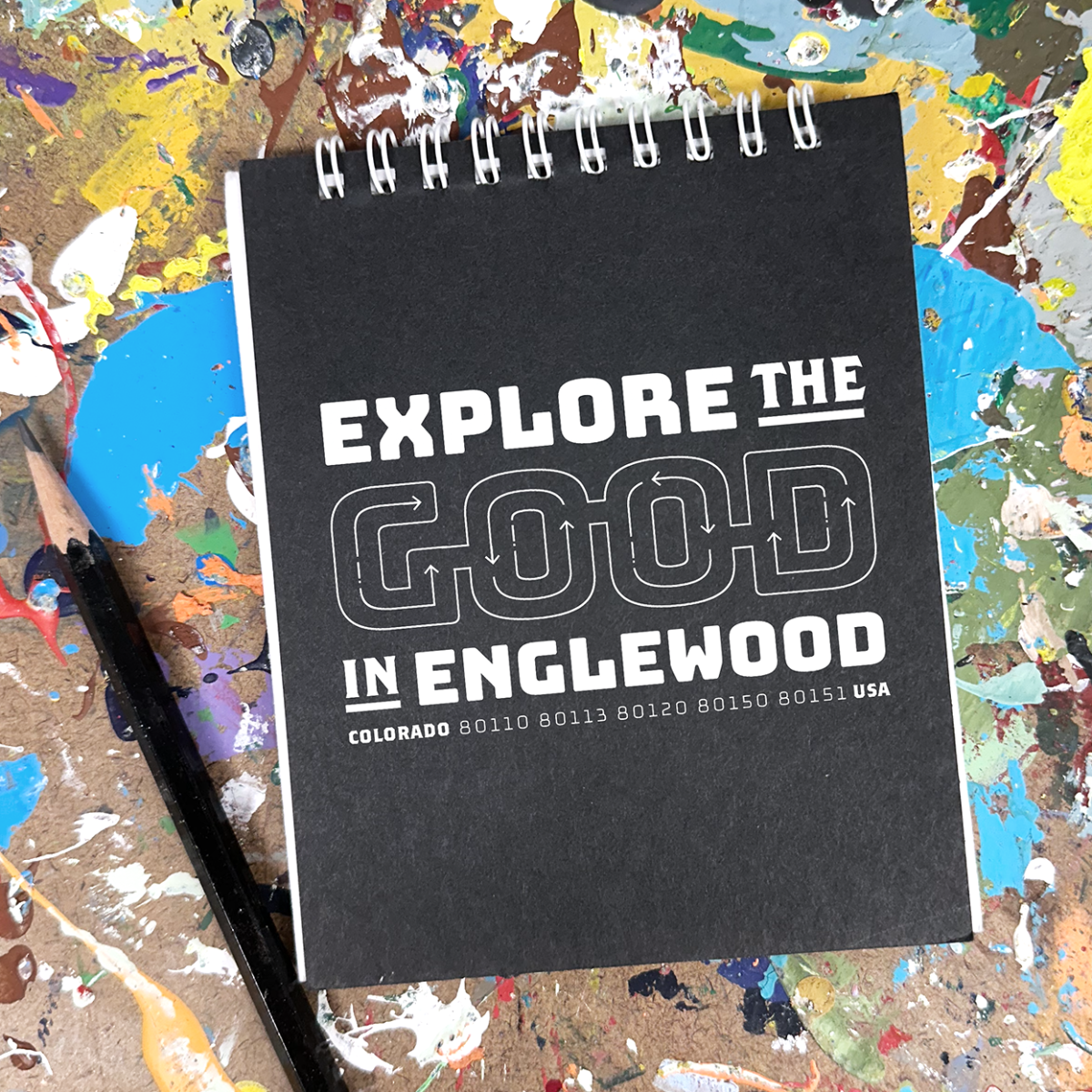 black t-shirt with white text: explore the good in englewood