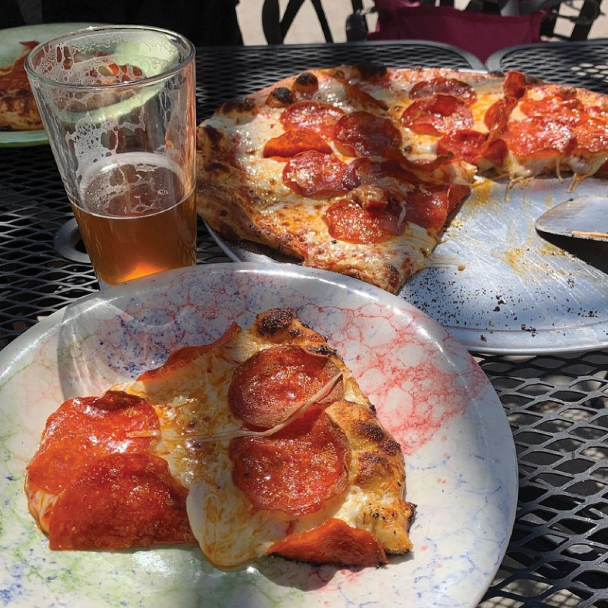 a plate of pepperoni pizza slices and a glass of beer behind